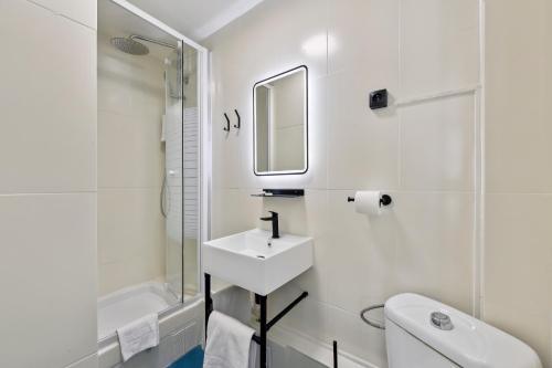 een witte badkamer met een wastafel en een spiegel bij Margot in Parijs