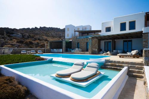 a swimming pool with two lounge chairs in front of a house at Amallini Suites Mykonos in Super Paradise Beach
