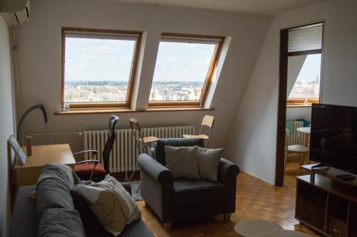 uma sala de estar com um sofá e uma televisão e duas janelas em Panorama Osijek em Osijek