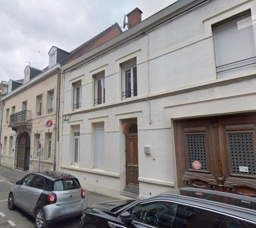 un coche aparcado frente a un edificio blanco en Haut 30 en Saint-Amand-les-Eaux