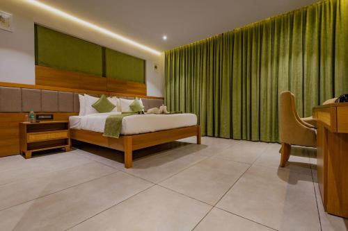 a bedroom with a bed with green curtains and a desk at Vanya in Bengaluru