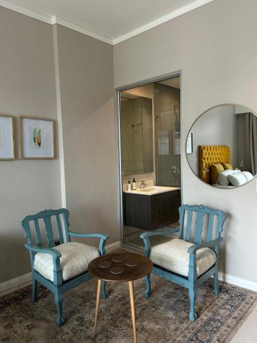 two chairs and a table in a bathroom with a mirror at Luxe Menlyn Oasis in Pretoria