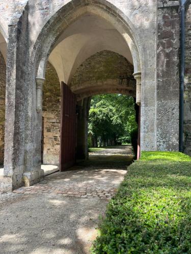 an archway in a stone building with a pathway at ABBAYE DE BLANCHELANDE in Neufmesnil