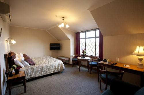 um quarto de hotel com uma cama, uma mesa e cadeiras em Distinction Coachman Hotel, Palmerston North em Palmerston North