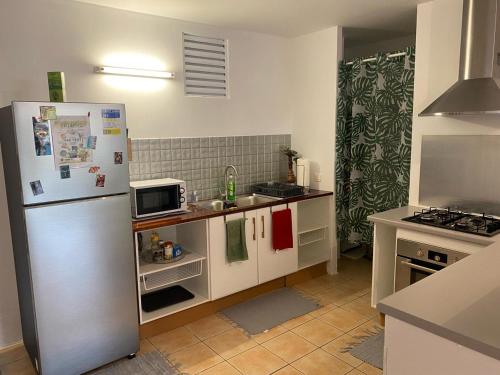 eine Küche mit einem Kühlschrank und einer Mikrowelle in der Unterkunft N'JOK Papeete in Papeete