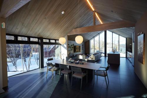 a dining room with a table and chairs and windows at Hakuba Hibiku Chalet by Jade Group in Hakuba