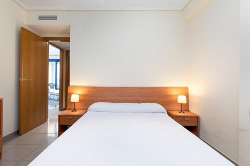 1 dormitorio con 1 cama blanca grande y 2 lámparas en Beach 75 metres away Playa a 75 metros, en Valencia