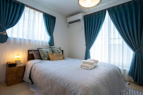 a bedroom with blue curtains and a bed with towels on it at シンプルでおしゃれなインテリアが光る4LDKの一軒家まるまる貸し切り！最大12名まで宿泊可能！ in Tokeshi