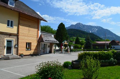 a building with a parking lot in front of a mountain at Hotel Garni Familie Gruber in Spital am Pyhrn