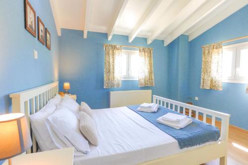 Un dormitorio con una cama blanca con paredes y ventanas azules en Villa Teresa, en Rodas