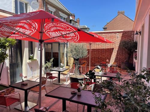eine Terrasse mit Tischen und einem roten Regenschirm in der Unterkunft Isvara Restaurant & Hotel in Breteuil