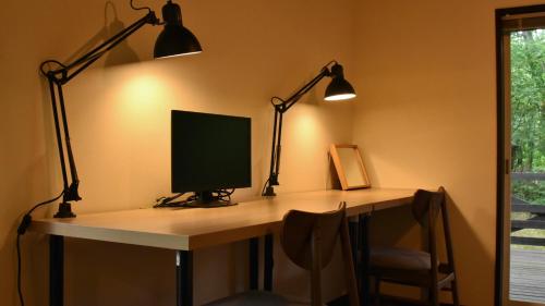 a desk with two lamps and a computer monitor on it at HANOOTO Kitakarauizawa in Tsumagoi