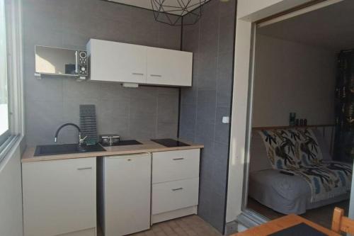 une cuisine avec des armoires blanches et un évier et un lit dans l'établissement Studio - Sète - 100m des plages, à Sète