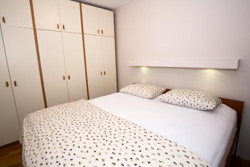een slaapkamer met een wit bed en witte kasten bij Cosy apartment near city centar and sea- Marina, Omiš in Omiš