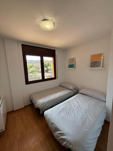two beds in a room with a window at Apartament l'Empalme d'Àger in Ager