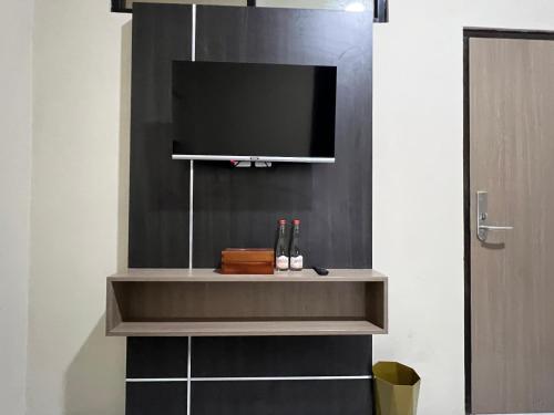 Elle comprend une télévision à écran plat sur un mur avec une étagère. dans l'établissement Brenn Hotel Semarang Mitra Reddoorz, à Semarang