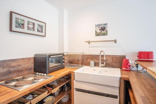 eine Küche mit einer Spüle und einer Mikrowelle in der Unterkunft La Bicoque - Maison de pêcheur - Cour ext in Étretat