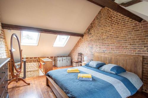 ein Schlafzimmer mit einem blauen Bett in einer Ziegelwand in der Unterkunft La Bicoque - Maison de pêcheur - Cour ext in Étretat