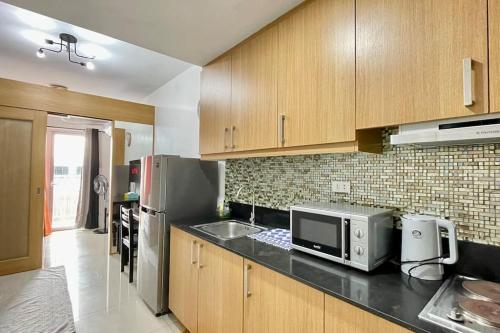 a kitchen with wooden cabinets and a sink and a microwave at Condo Suite Near NAIA 3 and Mall of Asia in Manila