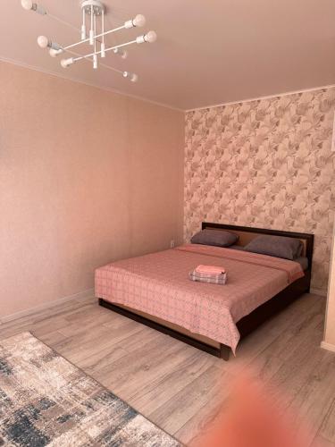 a bedroom with a bed and a chandelier at Центр. Аль-Фараби 100 in Kostanay
