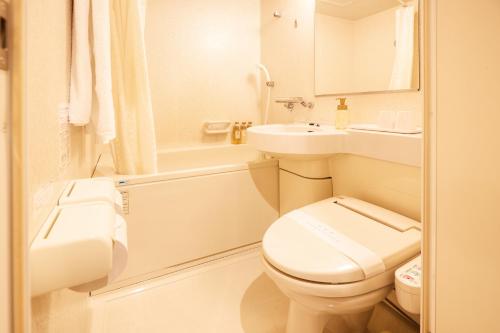 a white bathroom with a toilet and a sink at Naha Beach Side Hotel in Naha