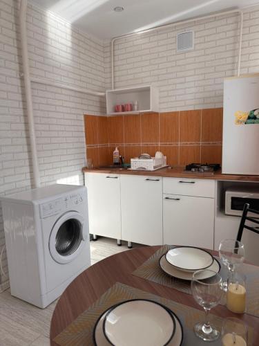 a kitchen with a washing machine and a table at Центр. Аль-Фараби 100 in Kostanay