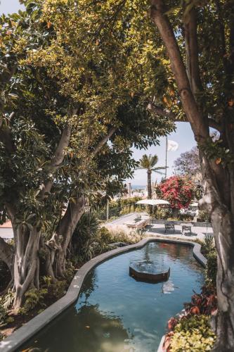 a pool with trees and a boat in it at VILLA QUINTA TORRINHA Rooms in Funchal