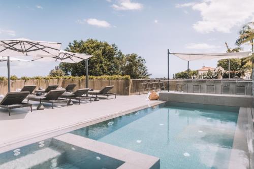 a swimming pool with chairs and umbrellas on a patio at VILLA QUINTA TORRINHA Rooms in Funchal