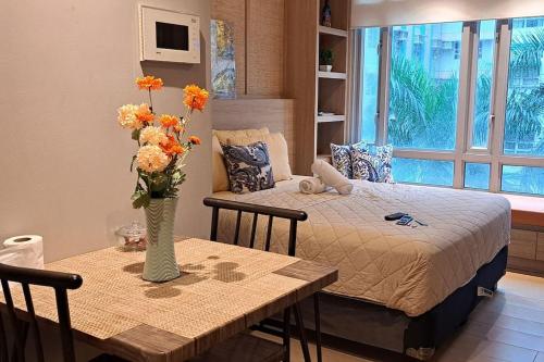 a bedroom with a bed and a table with a vase of flowers at Lovely Condo near NAIA T3 in Manila