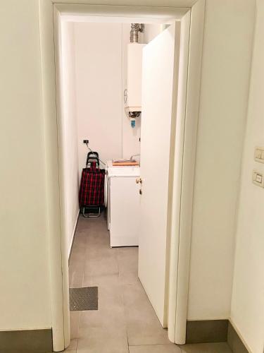 a hallway with a white kitchen with a red suitcase at Cavour 3 - Monolocale luminoso a due passi dalla Torre in Pisa