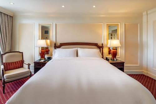 a large bed in a room with two lamps and a chair at The Westin Camino Real, Guatemala in Guatemala