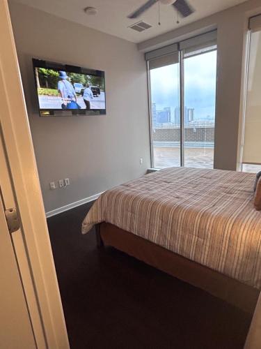 a bedroom with a bed and a tv on the wall at On The Go Stays(Penthouse) in Dallas