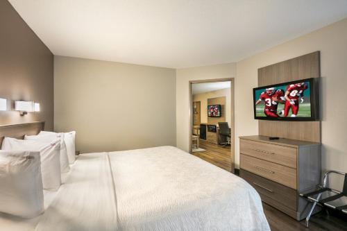 a bedroom with a white bed and a flat screen tv at Red Roof Inn PLUS+ Boston - Logan in Saugus