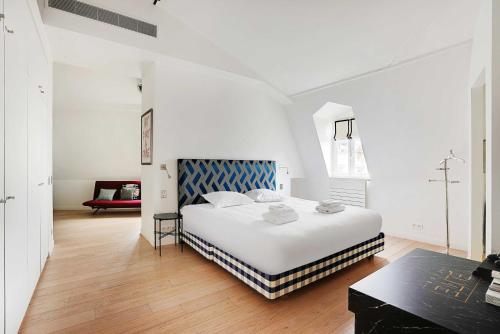 a white bedroom with a large bed and a table at Modern Loft 2BDR Place des Ternes in Paris