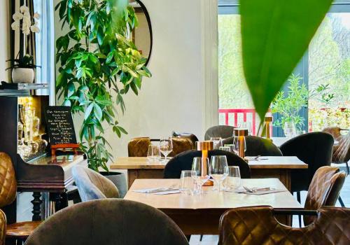 um restaurante com mesas de madeira, cadeiras e plantas em LOGIS Hôtel St Sylvestre em Aldudes