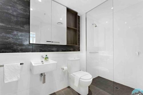 uma casa de banho com um WC, um lavatório e um espelho. em 18luxury apt in heart of chatswood free parking em Sidney