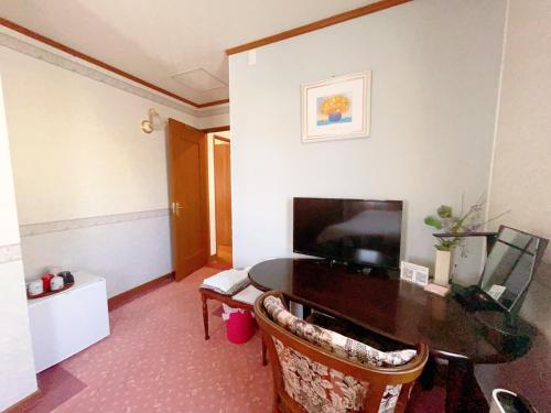 a living room with a table and a television at Otarunishikien in Otaru