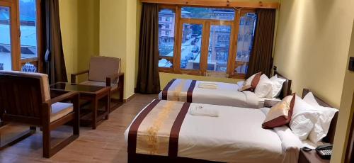 una camera d'albergo con due letti, una scrivania e una finestra di Punakha Residency a Punakha
