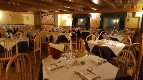 una sala da pranzo con tavoli e sedie con biancheria da tavolo bianca di Hotel Cielo Blu a Passo del Tonale