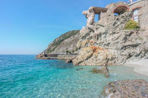 Eine Statue eines Mannes auf einer Klippe neben dem Meer. in der Unterkunft Villa degli Argentieri in Monterosso al Mare