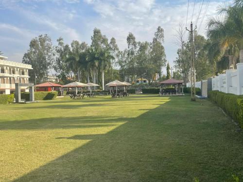 a large grass field with tables and umbrellas at Gold Nest Rubystone Heritage in Udaipur