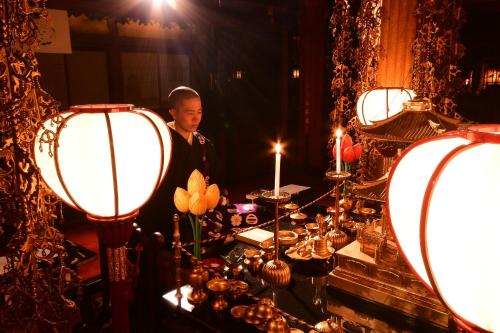 um homem de pé em frente a uma mesa com luzes em 高野山 宿坊 桜池院 -Koyasan Shukubo Yochiin- em Monte Koya