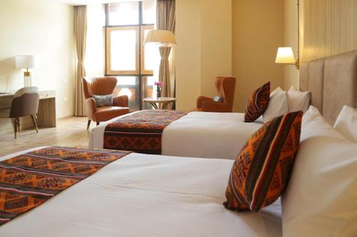 um quarto de hotel com duas camas e uma cadeira em Kaachi Grand Hotel em Paro