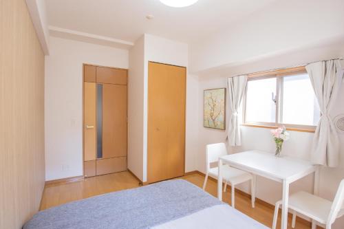 a bedroom with a bed and a table and a window at walk to JR Shibuya sta.-YoYY in Tokyo