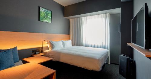 Habitación de hotel con cama y ventana en Grids Premium Hotel Kumamoto, en Kumamoto