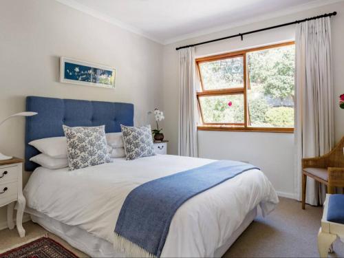 a bedroom with a bed with a blue headboard and a window at Casa Delfina in Simonʼs Town