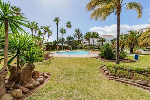 a swimming pool with palm trees in a park at Secret View Riviera Miraflores in La Cala de Mijas