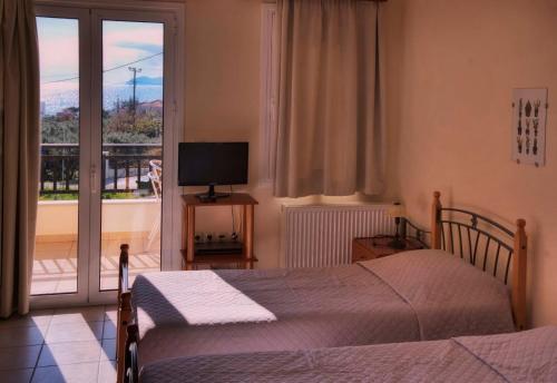 1 dormitorio con cama, TV y balcón en Apartments Hotel & Studios, Xifoupolis, en Monemvasia