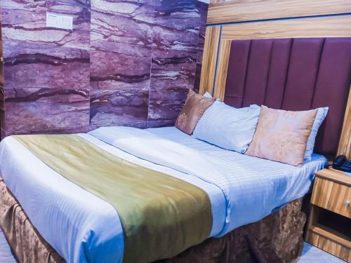 a bed in a room with a stone wall at Owee Hotel Exclusive Apartments & Suites in Lagos