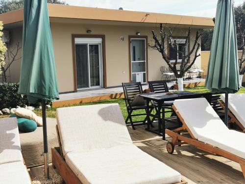 a patio with a table and chairs and umbrellas at Villa MATA - 600m² with Private Pool and Jacuzzi in Kalithies